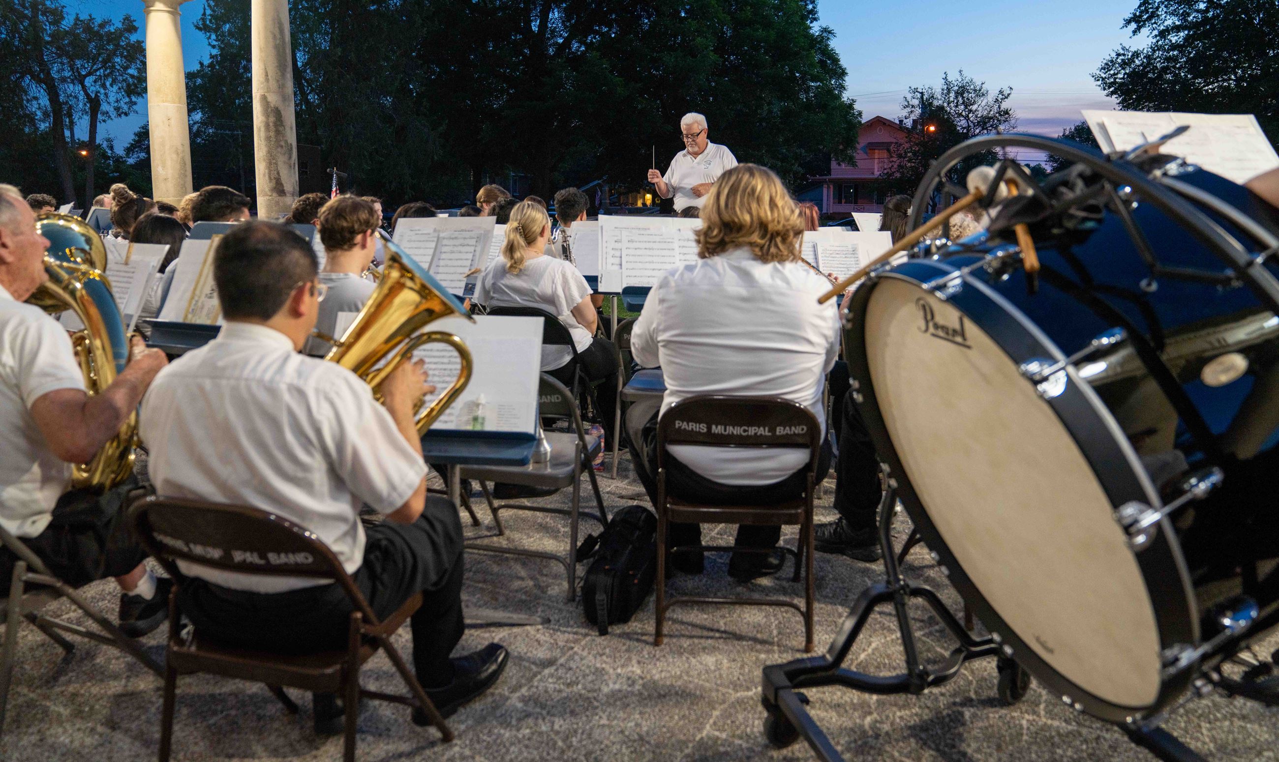Municipal band director leading band with tuba and percussion instruments and player in foreground